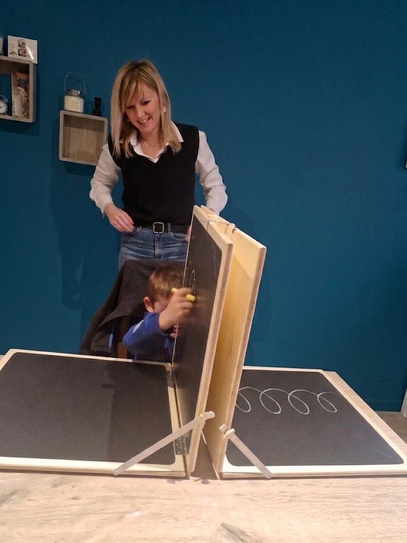 Émeline et un enfant devant le tableau de Mesker, un support à panneaux articulés, pendant un exercice de tracé de boucles